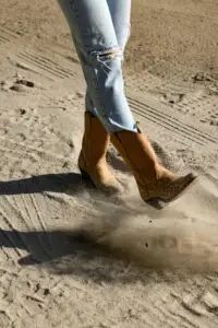 “Student boots kicking up dirt in outdoor arena symbolising grit and resilience”